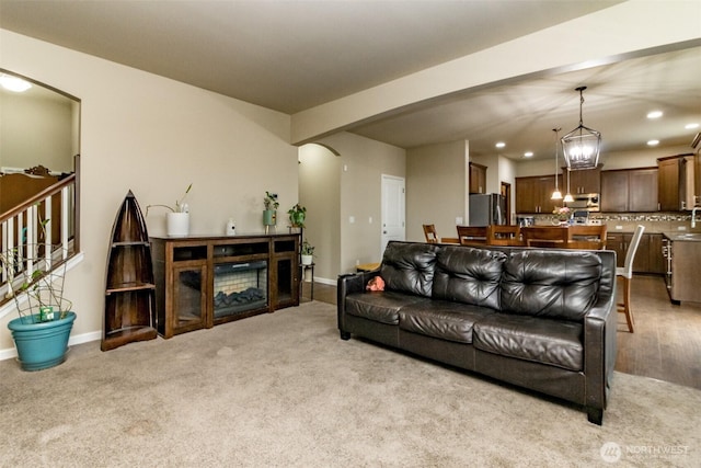 living area featuring arched walkways, light carpet, baseboards, and recessed lighting