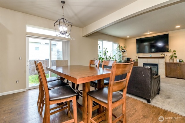 dining space featuring a tile fireplace, recessed lighting, wood finished floors, baseboards, and an inviting chandelier