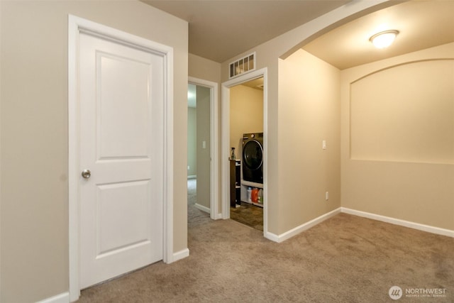 hall with washer / dryer, visible vents, arched walkways, baseboards, and carpet