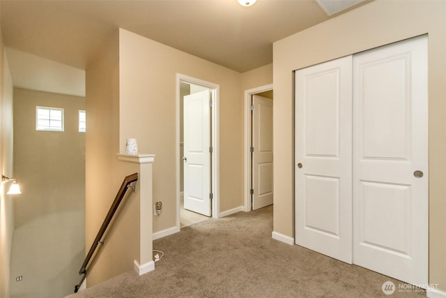 corridor with light carpet, baseboards, and an upstairs landing