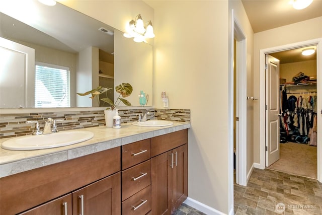 full bath featuring baseboards, a sink, visible vents, and decorative backsplash