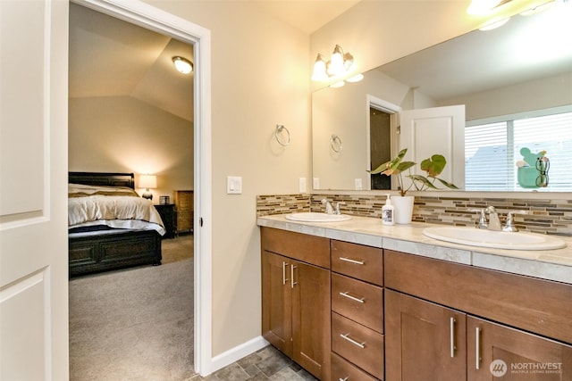 full bath with double vanity, ensuite bath, backsplash, and a sink