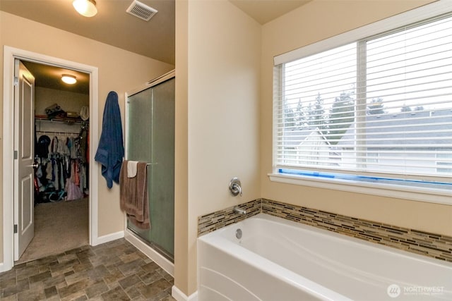 bathroom featuring a stall shower, a spacious closet, visible vents, and a garden tub