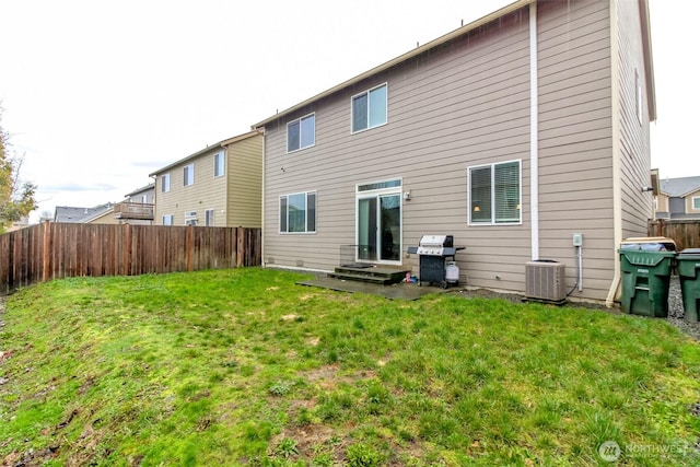 rear view of house with a lawn, cooling unit, and fence