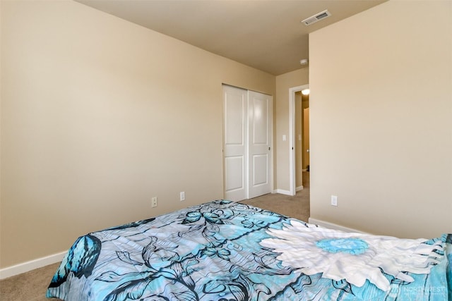 bedroom featuring a closet, visible vents, light carpet, and baseboards