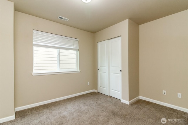 unfurnished bedroom featuring a closet, carpet flooring, visible vents, and baseboards