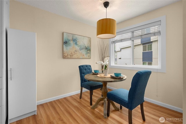 dining room with a textured ceiling, baseboards, and wood finished floors