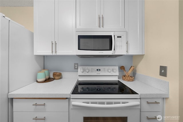 kitchen with white appliances, white cabinets, and light countertops