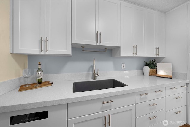 kitchen with white cabinetry, light countertops, and a sink