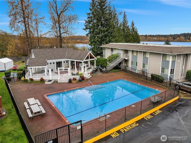 community pool featuring a patio area, fence, and a deck with water view