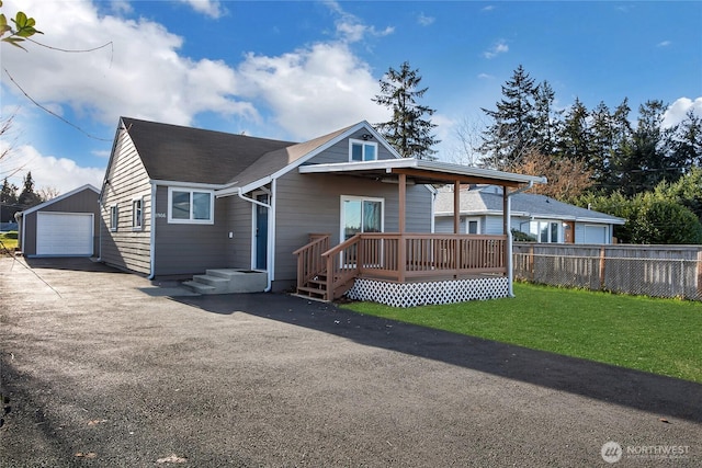 view of front of property featuring a front lawn, a garage, and an outbuilding