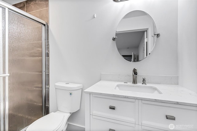 bathroom with vanity, a shower with door, and toilet