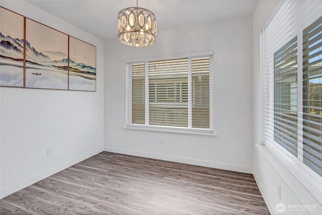 unfurnished room featuring hardwood / wood-style flooring and an inviting chandelier