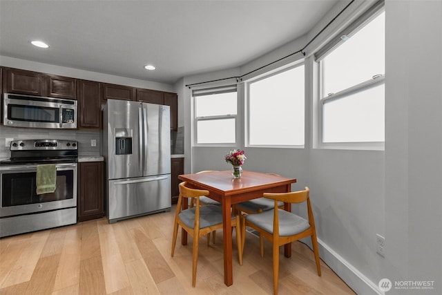 kitchen with appliances with stainless steel finishes, dark brown cabinetry, and light hardwood / wood-style flooring