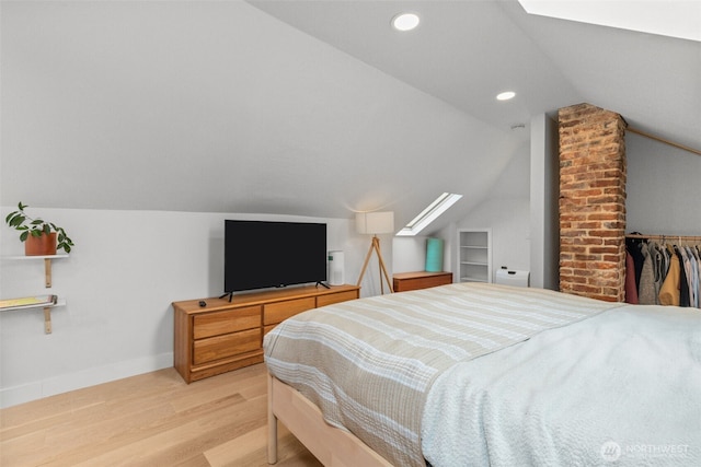 bedroom with light hardwood / wood-style floors, a closet, and vaulted ceiling with skylight