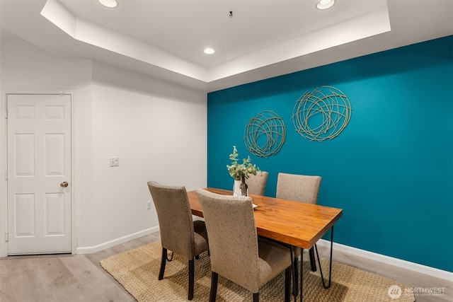 dining space with light hardwood / wood-style flooring and a raised ceiling