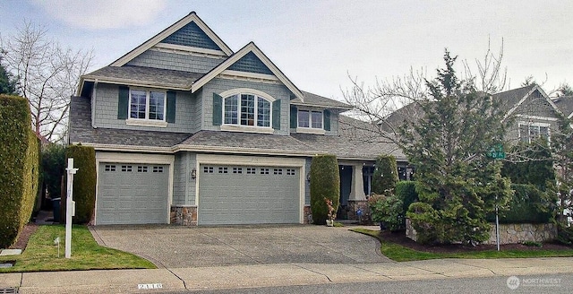 view of front facade with stone siding, driveway, and an attached garage