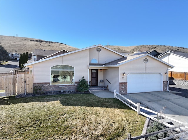 view of front of property featuring driveway, fence, a front yard, an attached garage, and brick siding