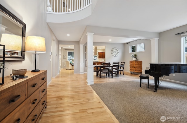 foyer featuring light wood-type flooring, ornate columns, baseboards, and recessed lighting