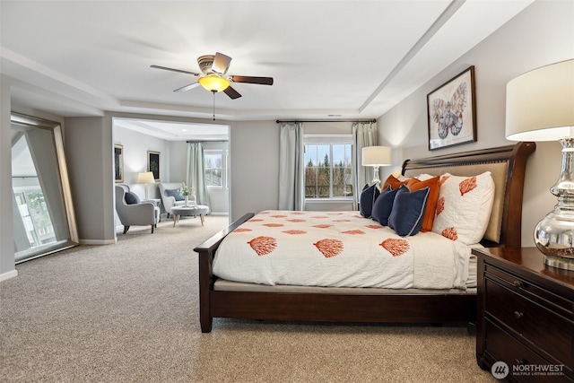 carpeted bedroom featuring a tray ceiling, baseboards, and a ceiling fan