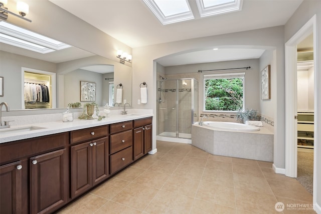 full bath featuring a garden tub, a spacious closet, a stall shower, and a sink