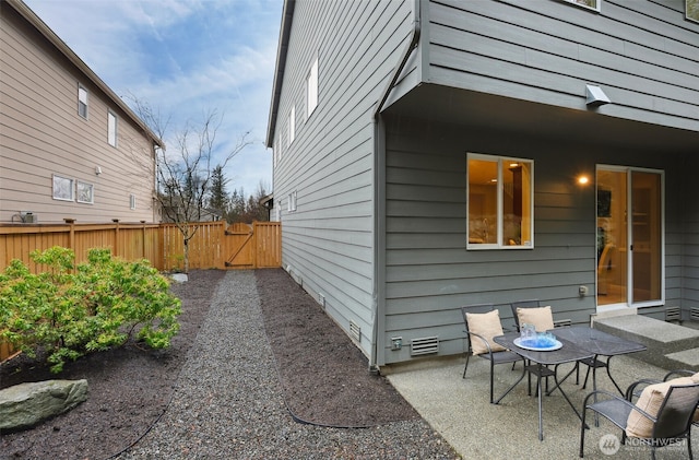 view of side of home featuring crawl space, a patio area, fence, and a gate