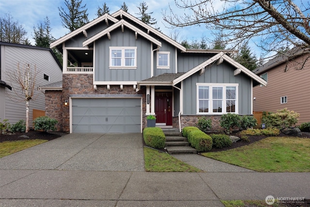 craftsman-style home with a balcony, a garage, stone siding, driveway, and board and batten siding