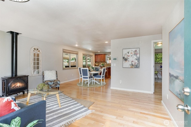 living room with recessed lighting, baseboards, light wood-style floors, and a wood stove