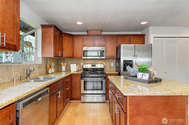 kitchen with light stone counters, decorative backsplash, appliances with stainless steel finishes, and a sink