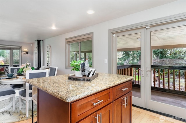 kitchen with light stone countertops, light wood-style floors, a kitchen breakfast bar, open floor plan, and a center island