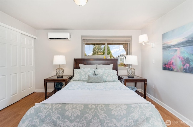 bedroom with a wall unit AC, wood finished floors, and baseboards