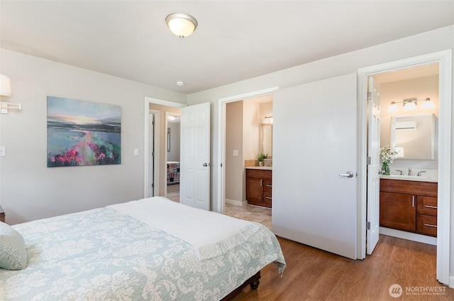 bedroom featuring ensuite bath, light wood-type flooring, and a sink