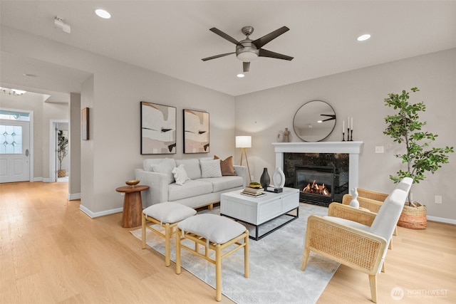 living room featuring a fireplace, recessed lighting, light wood-style flooring, a ceiling fan, and baseboards