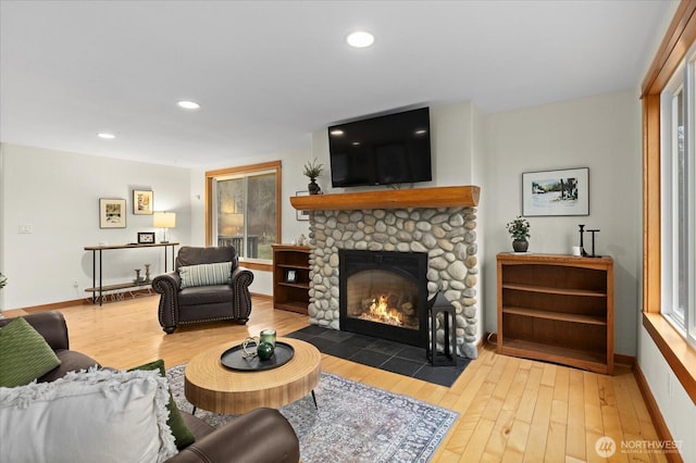 living area featuring recessed lighting, a stone fireplace, baseboards, and wood finished floors