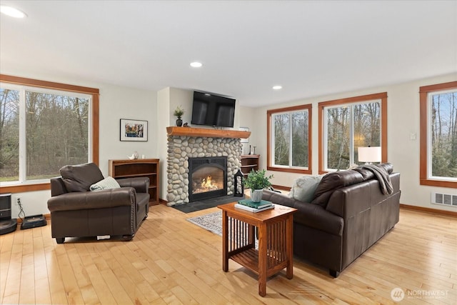 living area featuring a stone fireplace, recessed lighting, visible vents, baseboards, and light wood finished floors