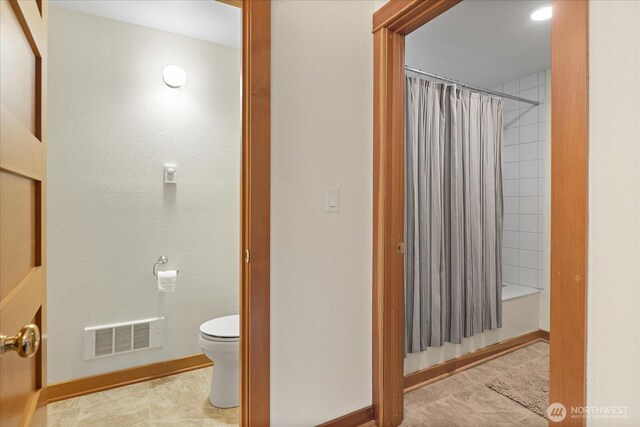 full bathroom with toilet, shower / tub combo, baseboards, and visible vents