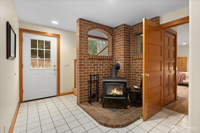 entryway with recessed lighting, a wood stove, baseboards, and light tile patterned floors