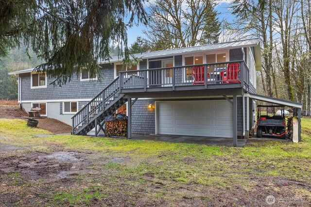 rear view of property featuring driveway, an attached garage, and stairway