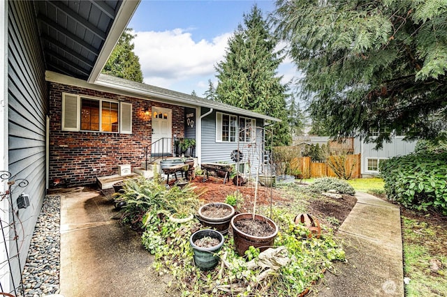 view of front of home featuring brick siding and fence