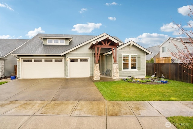 view of front of home with roof with shingles, concrete driveway, fence, a front lawn, and a garage