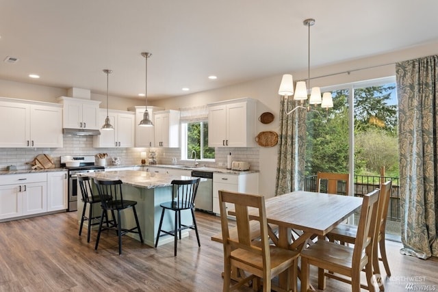 kitchen with stainless steel appliances, decorative light fixtures, a center island, sink, and white cabinetry