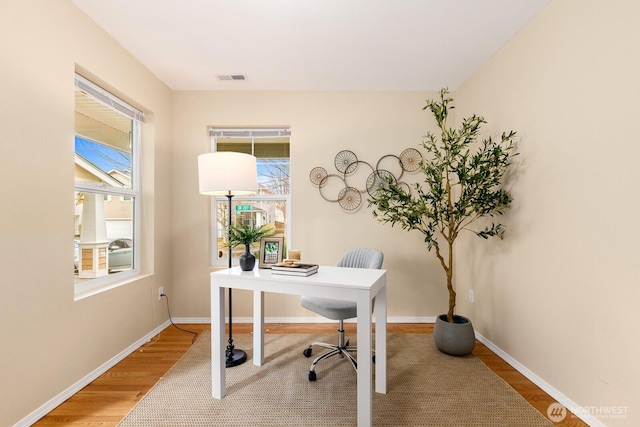 office area featuring visible vents, baseboards, and wood finished floors