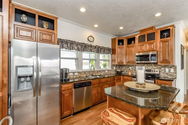 kitchen featuring a kitchen breakfast bar, stainless steel appliances, dark stone counters, a kitchen island, and sink