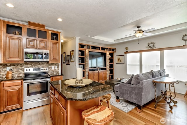 kitchen featuring appliances with stainless steel finishes, a kitchen island, light hardwood / wood-style floors, a breakfast bar area, and tasteful backsplash