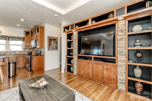 living room with a textured ceiling, ornamental molding, and light hardwood / wood-style flooring