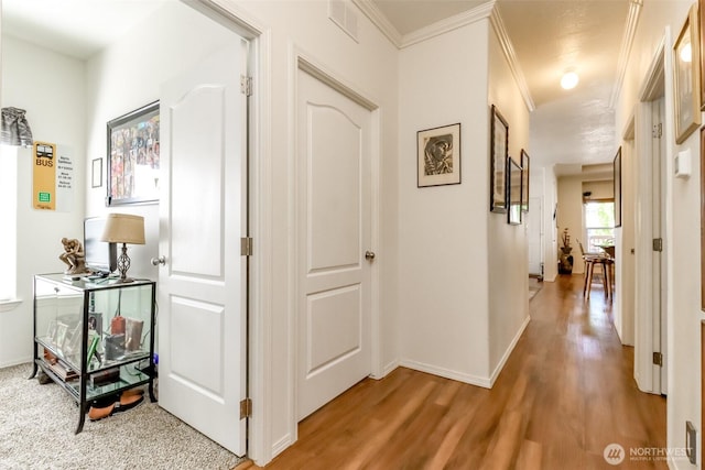 hall with hardwood / wood-style flooring and crown molding