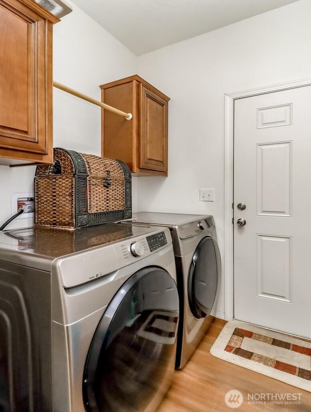 clothes washing area with light hardwood / wood-style floors, cabinets, and separate washer and dryer