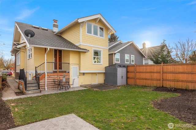 back of property featuring an outdoor structure, fence, roof with shingles, a lawn, and a chimney