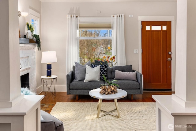 living room featuring a wealth of natural light, a brick fireplace, and wood finished floors