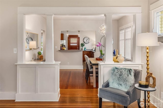 sitting room with decorative columns, baseboards, and wood finished floors